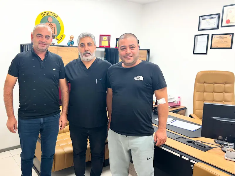 Op. Dr. Selahattin Yitgin, başarılı geçen hemoroid tedavisi sonrası sağlığına kavuşan ve memnuniyetini dile getiren mutlu hastalarıyla birlikte kliniğinde gülümsüyor.