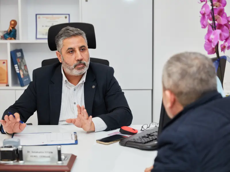 Op. Dr. Selahattin Yitgin, İstanbul'daki kliniğinde hemoroid muayenesi öncesinde hastasının şikayetlerini dikkatle dinlerken ve süreç hakkında bilgi verirken.